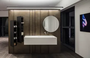 Modern bathroom suite with minimalist design featuring metallic paneling, floating sink, and large round mirror.