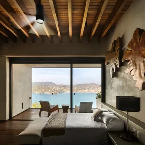 A modern bedroom featuring wooden furnishings and a view of the ocean.