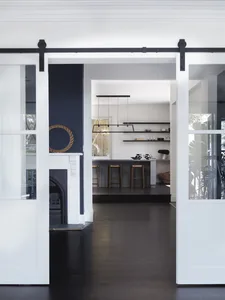 Modern kitchen designed with black and white color scheme, featuring wood-road-hardwood flooring and sleek white cabinetry.
