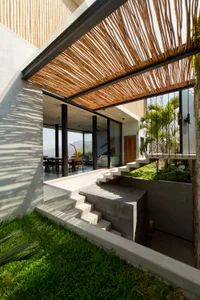 A modern house with a concrete exterior, featuring a layered wooden roof structure.