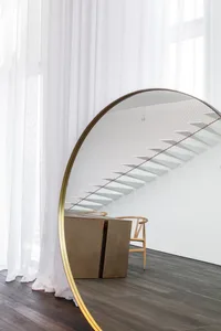 Modern interior design featuring a glass staircase with metal railing and wooden accents.