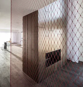 A modern living room with a glass fireplace and red wire mesh partition.