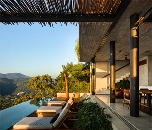 A modern patio with glass railings, metal chairs, and wooden loungers.