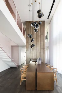 Modern restaurant interior with metal and wooden dining area, concrete backdrop, and hanging lamps.
