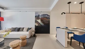 Modern living room with neutral-tones color palette, featuring a white sofa adorned with various cushions, a wooden stool, a 