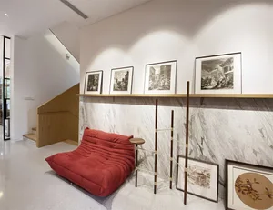 A modern living room featuring a red sofa, marble wall, and framed artwork.