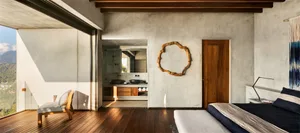 Modern minimalist bedroom with concrete walls, wooden floor, and dark bedding.