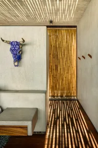 A minimalist interior with a concrete bench, bamboo wall, and geometric lighting shadows.