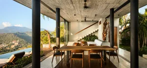 Modern minimalist living room with concrete walls, wooden floors, and a large window overlooking a scenic mountain view.