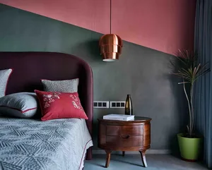 A modern bedroom featuring a color-block wall with a combination of pink and dark green, a wooden nightstand, and decorative 