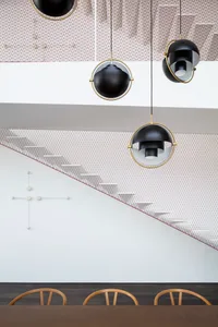 A modern dining room with contemporary lighting fixtures and a geometric staircase.