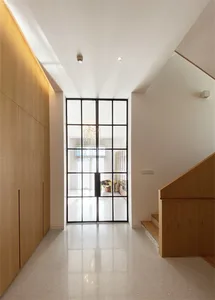 Modern interior design featuring glass door with metal frame, wooden panels, and chandelier