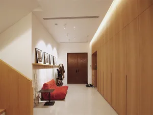 Minimalist living room designed with natural wood elements and a red cushioned seating area.