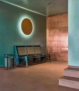 A modern living room featuring a concrete floor, copper wall, and wooden furniture.