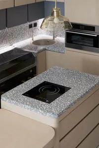 Modern kitchen featuring a terrazzo countertop with an integrated cooktop.