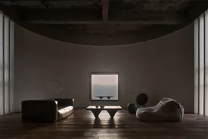 A minimalist living room with concrete furniture and a large window overlooking a serene landscape.