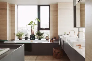 Modern bathroom featuring light wood tiles, a large window with green plants, and a floating vanity with white sinks.