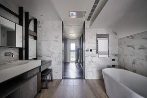 A modern bathroom with marble walls and a freestanding bathtub.