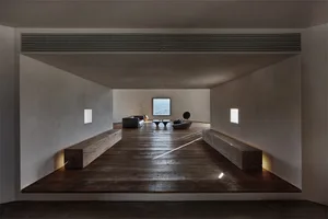 Modern living room featuring minimalist wooden furniture and concrete floor and walls with a large window.