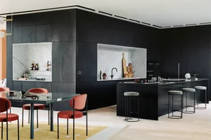 A modern kitchen featuring marble countertops and dark wooden cabinets.
