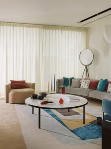 A modern living room with a circular coffee table, grey sofa, and fabric armchair.