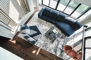 Modern living room interior designed with a contemporary style, featuring a blue sofa, armchair, and coffee table on a patter
