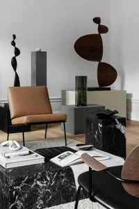 Modern, minimalist living room featuring polished marble furniture and sculptures.