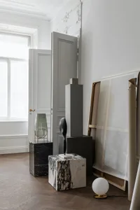 Modern interior with sculptures displayed on marble pedestals against a white wall.