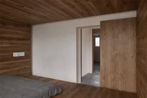 A minimalist bedroom featuring wood-paneled walls and a carpeted floor.