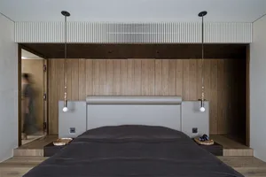 A minimalist bedroom with a wooden headboard and wall paneling.