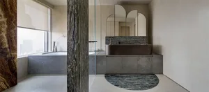 Modern bathroom with marble and concrete finishes, featuring a round mirror and a freestanding bathtub.
