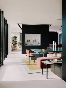 Modern living room featuring a black and white bar area with metallic accents, glass table, and pink chairs.