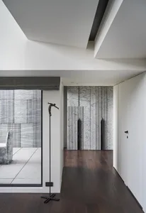 Modern interior design featuring a marble corridor with dark wooden floors and a sculpture.