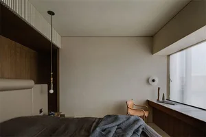 A modern minimalist bedroom with a bed, chair, and large window.