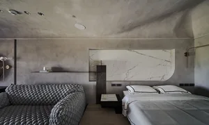 Modern minimalist bedroom with concrete walls, marble headboard, and minimalist bedding.