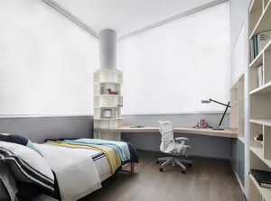 A modern bedroom with a wooden bed frame, a white desk, and built-in shelves.