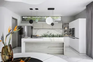 A modern kitchen featuring marble countertops and stainless steel appliances, with a minimalist and sleek design.