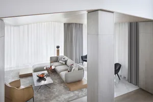 Modern interior design featuring a light wood floor, concrete accents, glass windows, and a fabric sofa.