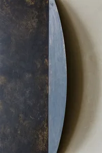 A modern metallic circle with a textured, oxide-coated surface.