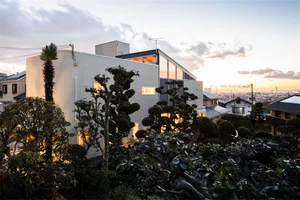 A modern residential house with metallic exterior, glass windows, and concrete accents.