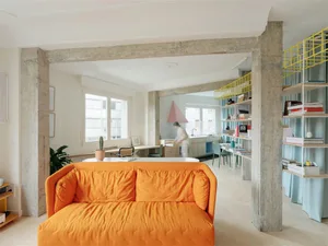 A modern living space featuring orange couches and concrete columns.