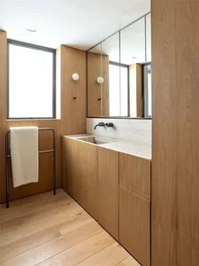 Modern minimalist bathroom with wood walls and flooring and a floating sink with a marble countertop.