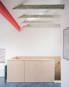 A minimalist interior design featuring exposed concrete beams and white walls.
