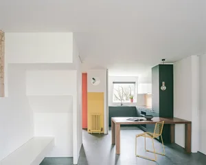 Modern minimalist residential kitchen with white walls, a wooden dining table, and a yellow radiator.