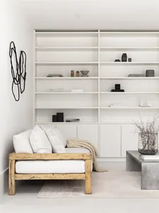 A minimalist living room with a wooden sofa, concrete coffee table, and white shelves.