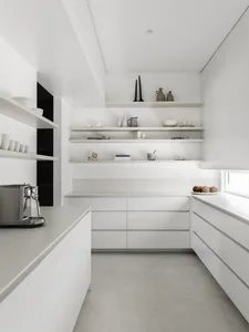 A modern, minimalist kitchen with white cabinets, stainless steel appliances, and white countertops.