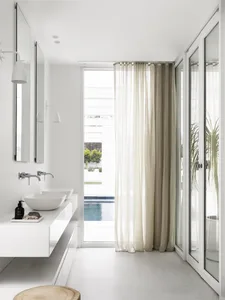A modern bathroom with white walls, glass walls, marble elements, a floating vanity, and a curtain.