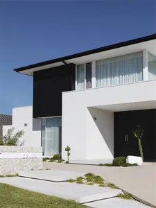 Modern house with white and concrete exterior, large windows, and a minimalist design.