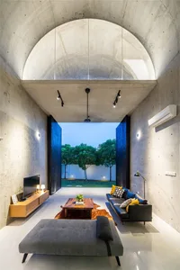 A modern minimalist living room with concrete walls and a large arched window.