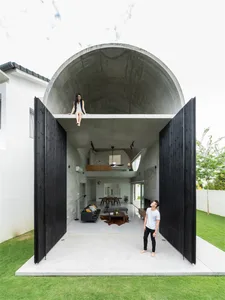 A minimalist house with a concrete tunnel structure, featuring a spacious interior with large windows and a sleek, modern des